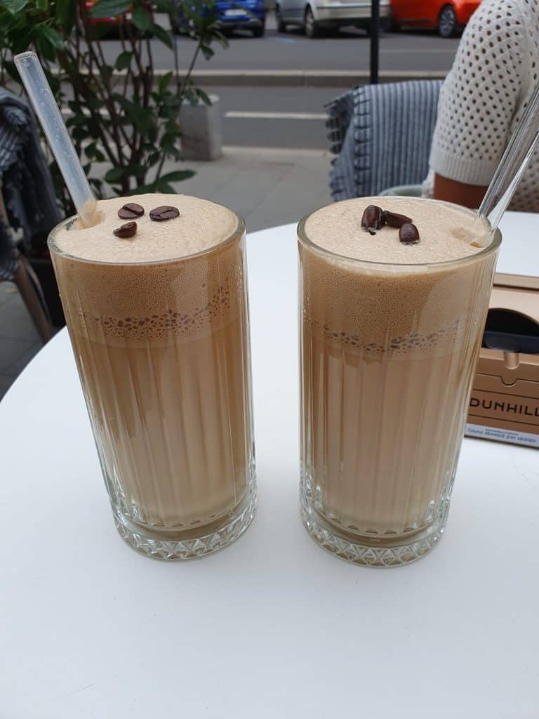 two iced coffees in tall glasses with coffee beans on top